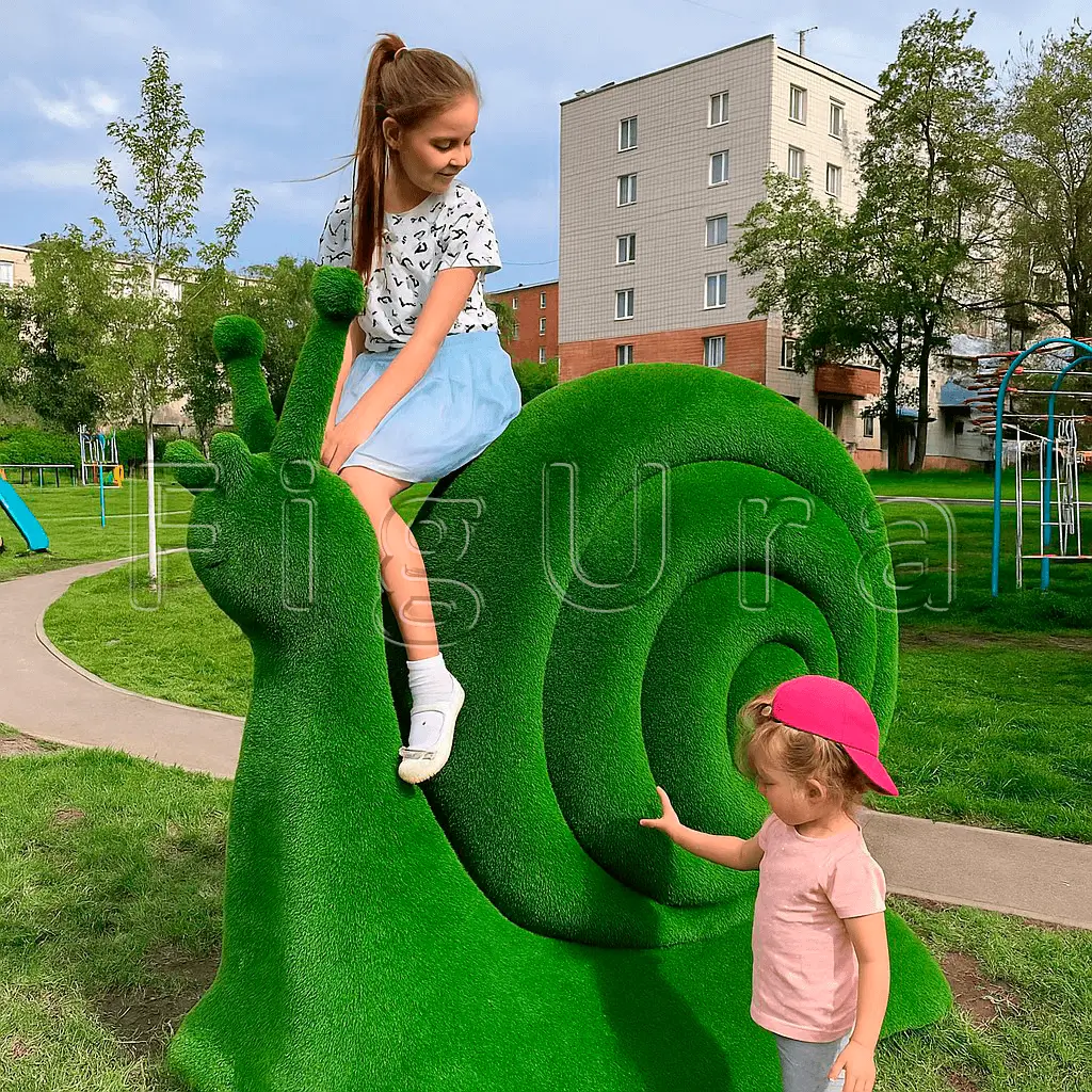 Дети играют на зеленой искусственной фигуре улитки на площадке